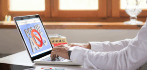 Hands typing on a laptop with a screen showing 'Pop-up Ads' crossed out by a red circle and slash, indicating pop-up ads are blocked.