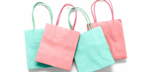 Three small pastel-colored gift bags are stacked slightly askew on a white background.