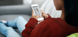 A woman is sitting on a couch holding a remote control